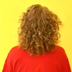 Cette image représente une jeune femme de dos. On y voit ses cheveux bouclés sublimés après une prestation chez kaaaruslos.com à Marseille, le salon de coiffure pour cheveux bouclés